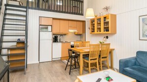 A compact living space with a kitchen, dining area, and a staircase leading to an upper level.