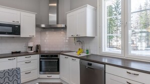 A modern kitchen with white cabinets, stainless steel appliances, and a window with a view of trees. - Villa elisabet by Interhome (Ristiina)