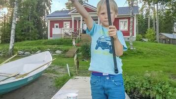 Eine Holzsteg mit einem Boot, einem Haus im Hintergrund und einer Person, die eine Angel hält.