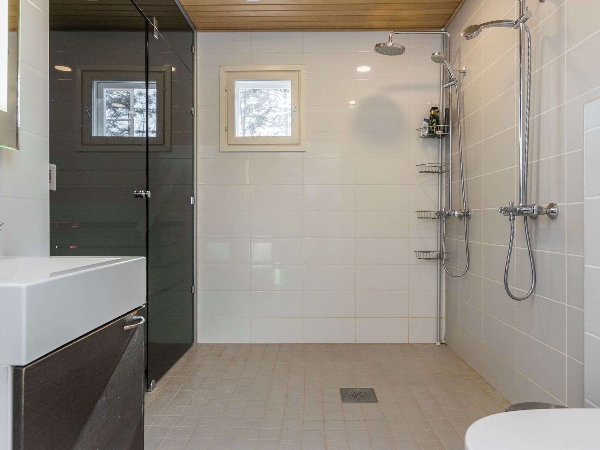 Une salle de bain moderne avec une douche à parois de verre, des toilettes et un lavabo avec un meuble sombre.