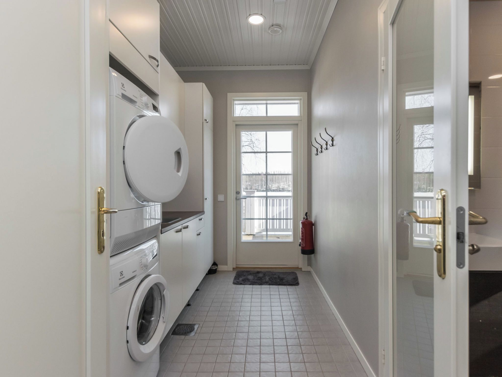 A laundry room with a washing machine, dryer, and a fire extinguisher mounted on the wall.