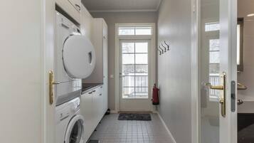 A laundry room with a washing machine, dryer, and a fire extinguisher mounted on the wall.