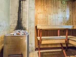 Uma sauna com aquecedor de pedra, banco de madeira e chão revestido de azulejos.