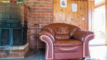 Un sillón de cuero en una habitación con chimenea de ladrillo y paredes de madera.
