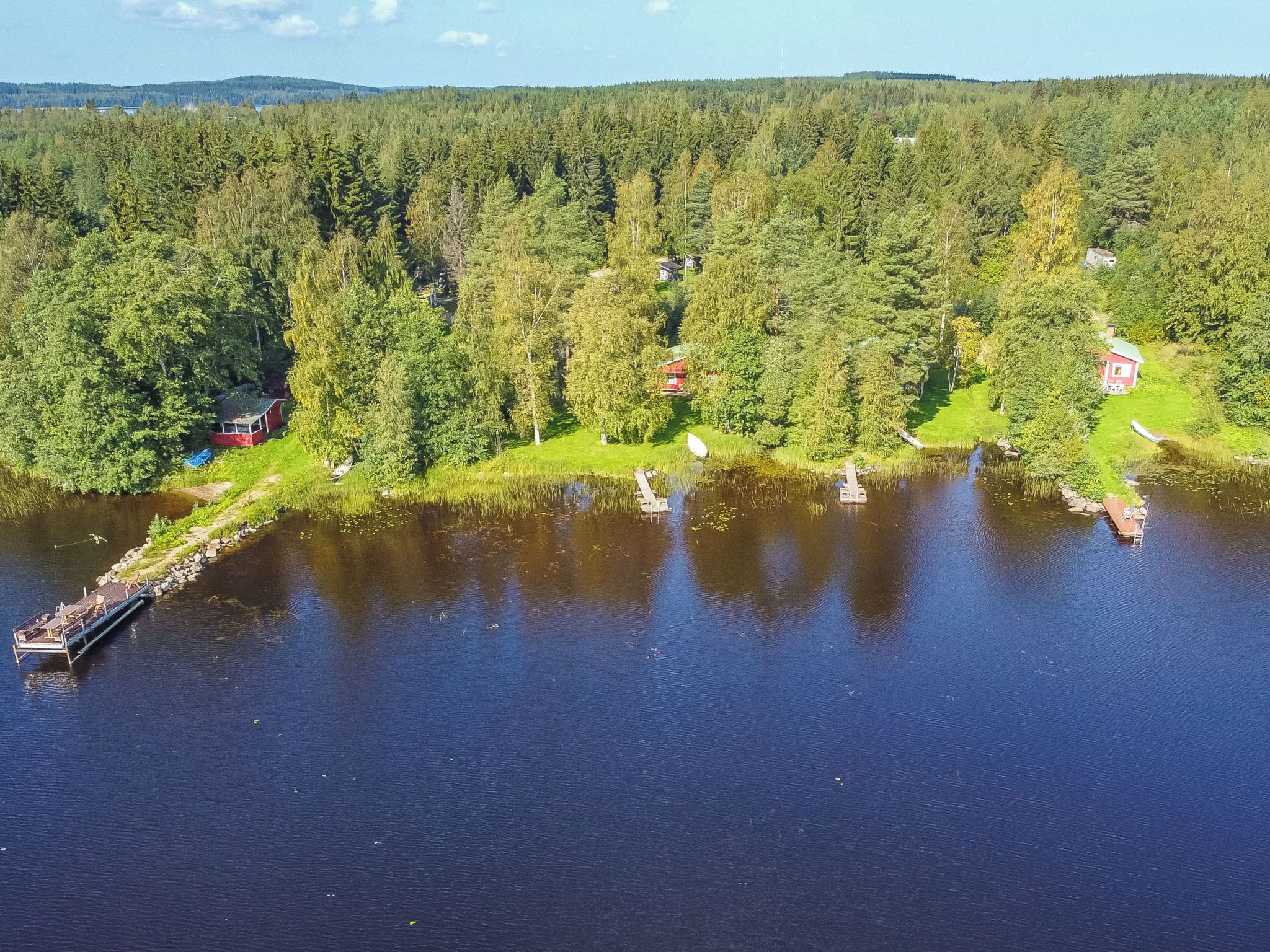 Une propriété au bord du lac, dotée d’un quai, d’une petite maison et bordée d’une forêt dense.