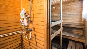 Un sauna de madera con un cabezal de ducha, un estante con artículos de aseo y un banco.
