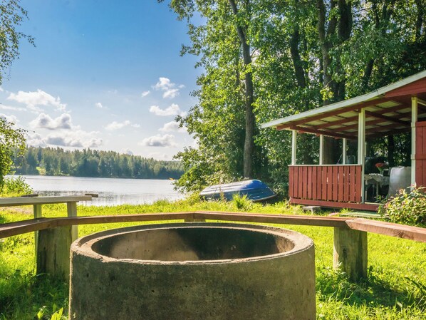 Vista al lago con muelle de madera, parrilla y zona de estar cubierta.