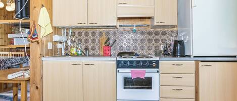 A kitchen with wooden cabinets, a stove, and a refrigerator.