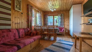 Un interior acogedor de cabaña con piso de madera, un sofá, una mesa de comedor y un televisor.