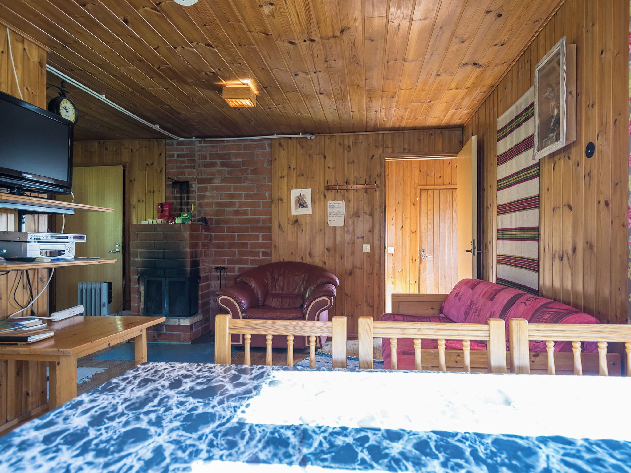 A cozy cabin interior with a fireplace, wooden furniture, and a bed with a blue and white patterned bedspread.