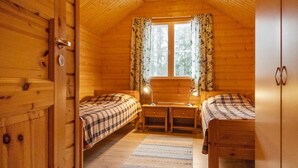 Acogedora habitación tipo cabaña con dos camas, un escritorio y una ventana con cortinas.