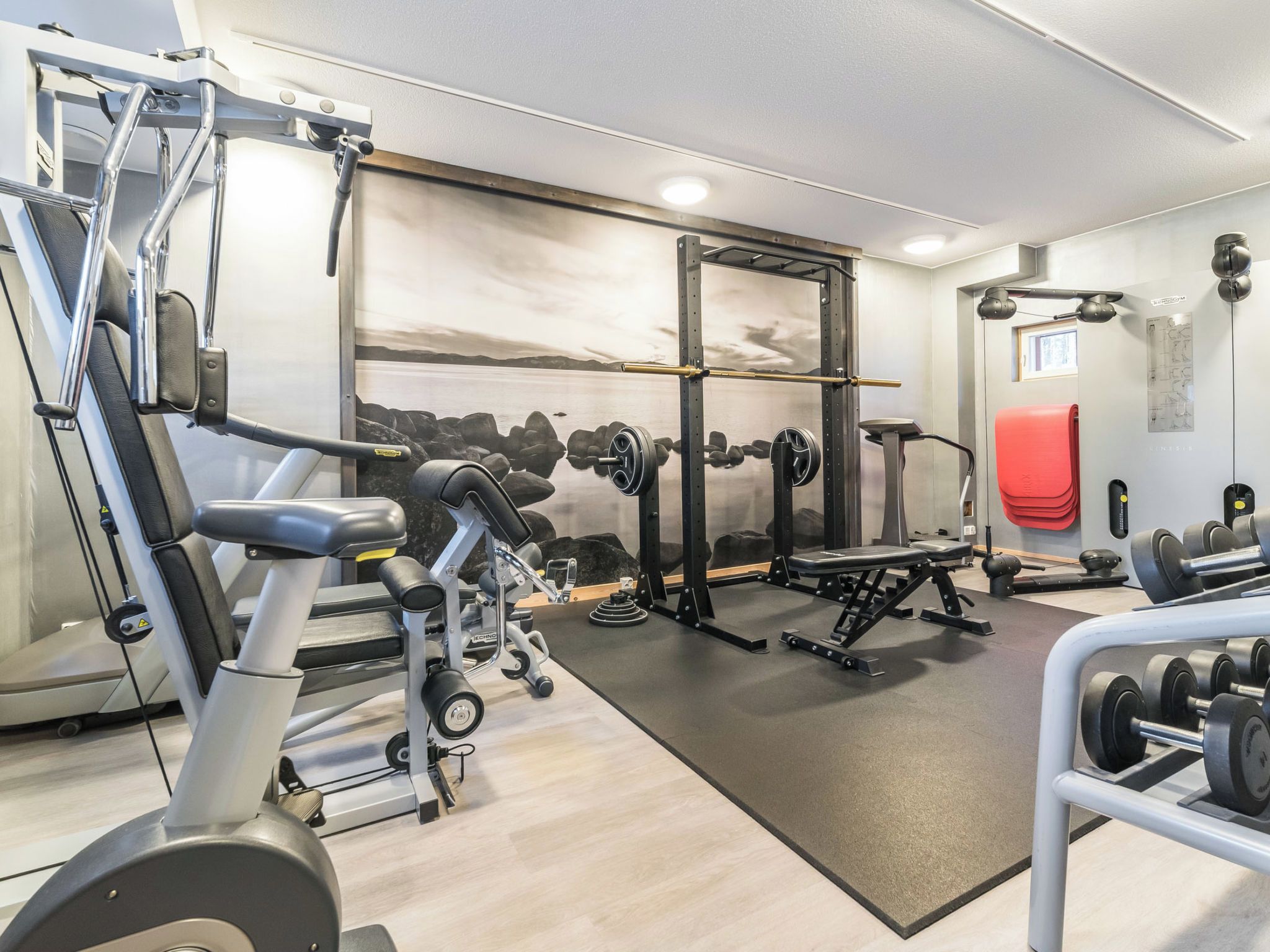 Une salle de sport équipée de divers appareils d’entraînement, notamment un banc de développé couché, des haltères et un support à squats.