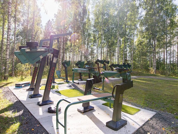 Des appareils de musculation en plein air dans un parc, avec des arbres en arrière-plan.