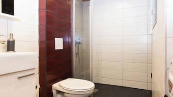 A bathroom with a toilet, a shower, and a sink.