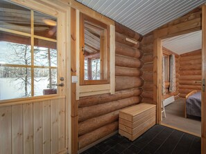 Ein Holzblockhaus-Innenraum mit einer hölzernen Bank, einem kleinen Tisch und einer Tür zu einem anderen Raum.