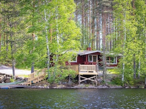 Een vakantiehuisje met een houten terras en een trap naar een steiger.
