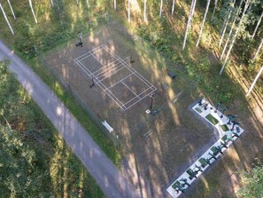 Une vue aérienne d’un court de tennis entouré d’arbres, avec un chemin menant à celui-ci.
