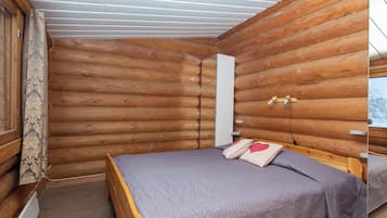 Quarto de cabana de madeira com uma cama, janela e teto de madeira.