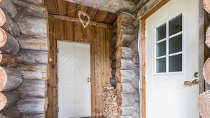 Eingang einer Blockhütte mit Holztür und kleiner Veranda.