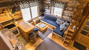 Ein gemütliches Blockhaus-Interieur mit einer Couch, Holztischen und einem Essbereich.