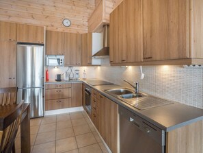 A modern kitchen with wooden cabinets, stainless steel appliances, and a tiled backsplash. - Ylläksen rinnemäki b by Interhome (Ylläsjärvi)