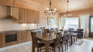 A modern kitchen with wooden cabinets, a dining table, and chairs. - Ylläksen rinnemäki b by Interhome (Ylläsjärvi)