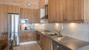 A modern kitchen with wooden cabinets, stainless steel appliances, and a tiled backsplash. - Ylläksen rinnemäki b by Interhome (Ylläsjärvi)