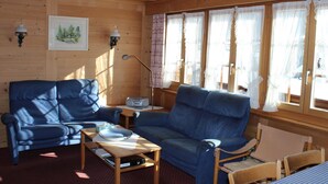 Een gezellige kamer met een blauwe bank, een tafeltje met een schaal en een afstandsbediening, en een lamp.
