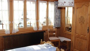Een houten kamer met een bed, een stoel, een tafel en een kledingkast.