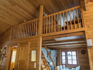 L’intérieur d’une cabane en bois comprend une chambre à coucher située en mezzanine, un coin cuisine et un espace repas.
