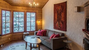 Interior acogedor de una cabaña de madera con sofá, una mesa redonda y una chimenea.