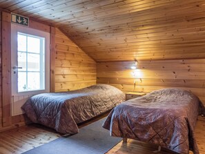 A cabin with two beds, a window, and a door with an emergency exit sign.