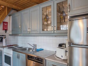 A kitchen with light blue cabinets, a stainless steel dishwasher, a toaster, and a refrigerator.