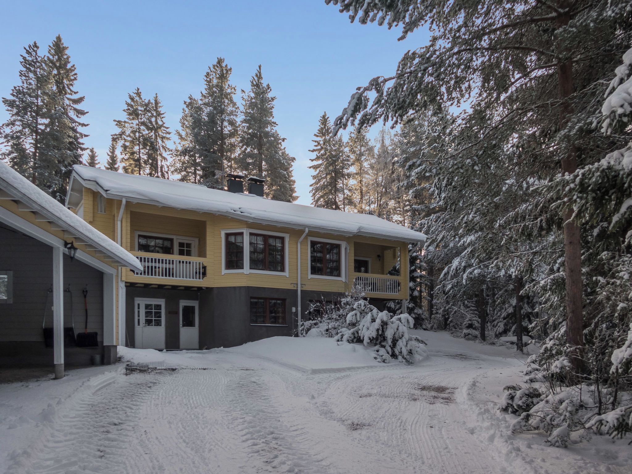 Un bâtiment à deux étages, dont le toit est recouvert de neige, et une allée menant à l’entrée.