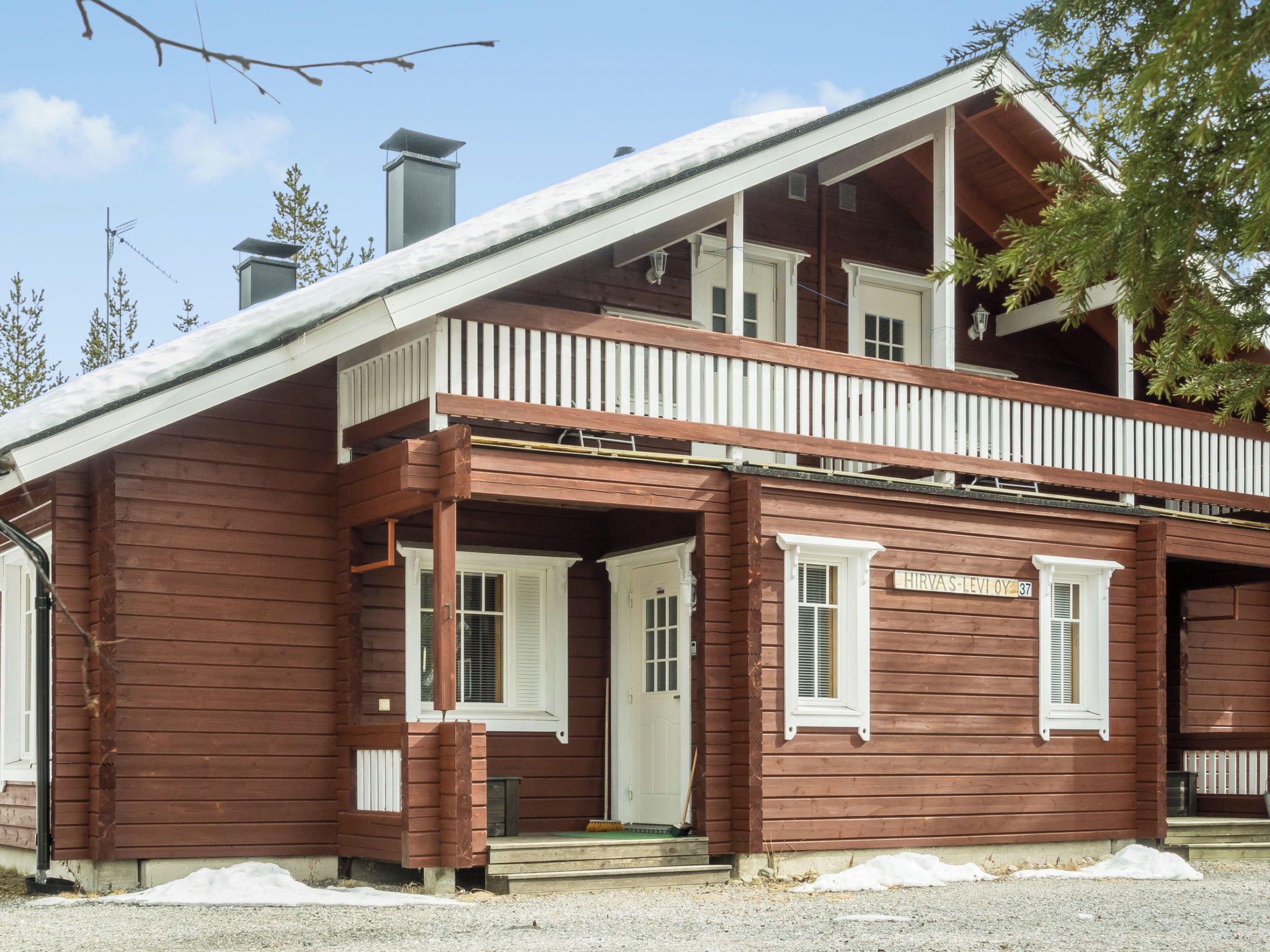 A two-story wooden building with a balcony, a sign with the name 'Hirvas-Levi Oy', and a chimney.