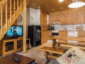 A wooden interior with a TV, wooden cabinets, a bench, and a kitchen area.