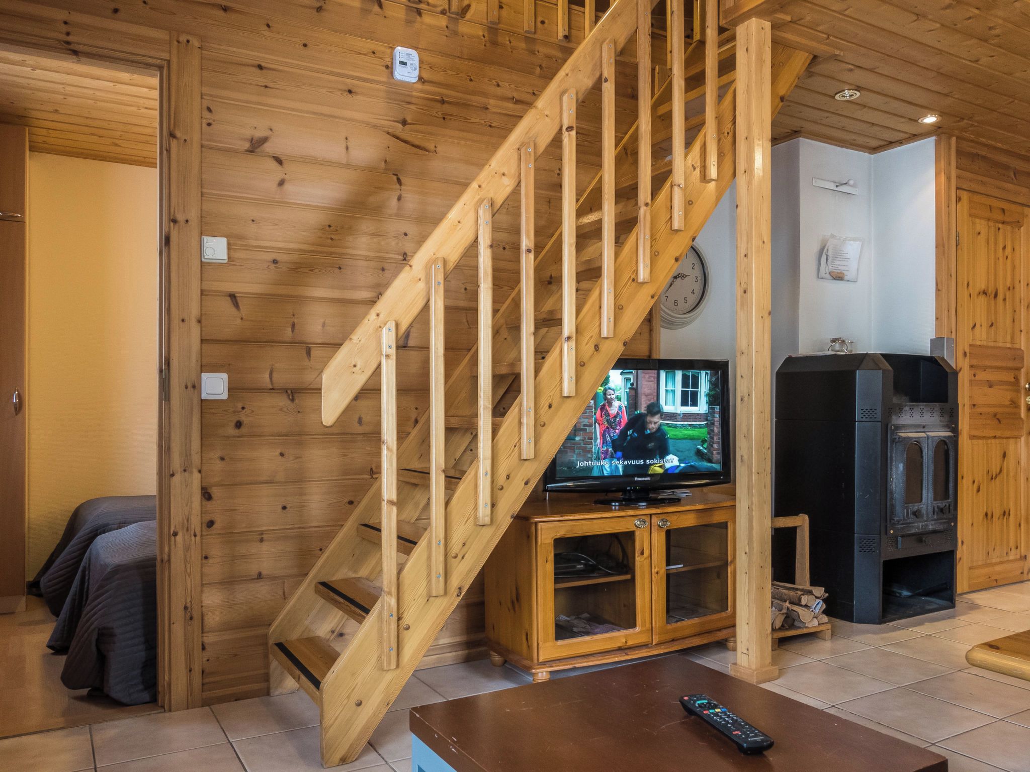 A wooden staircase leading to a loft area with a television and a fireplace.