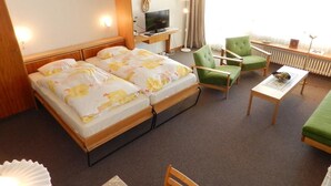 A hotel room with two beds, a TV, a desk, and two green armchairs. - La Sarine 222 by Interhome (Gstaad)