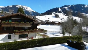 A traditional chalet with a balcony, surrounded by snow-covered mountains and a clear sky. - La Sarine 222 by Interhome (Gstaad)