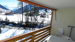 A balcony with a wooden railing overlooking a snowy landscape with mountains in the background. - La Sarine 222 by Interhome (Gstaad)