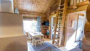 L’intérieur d’une cabane en bois comprend un coin repas, un téléviseur et une échelle.