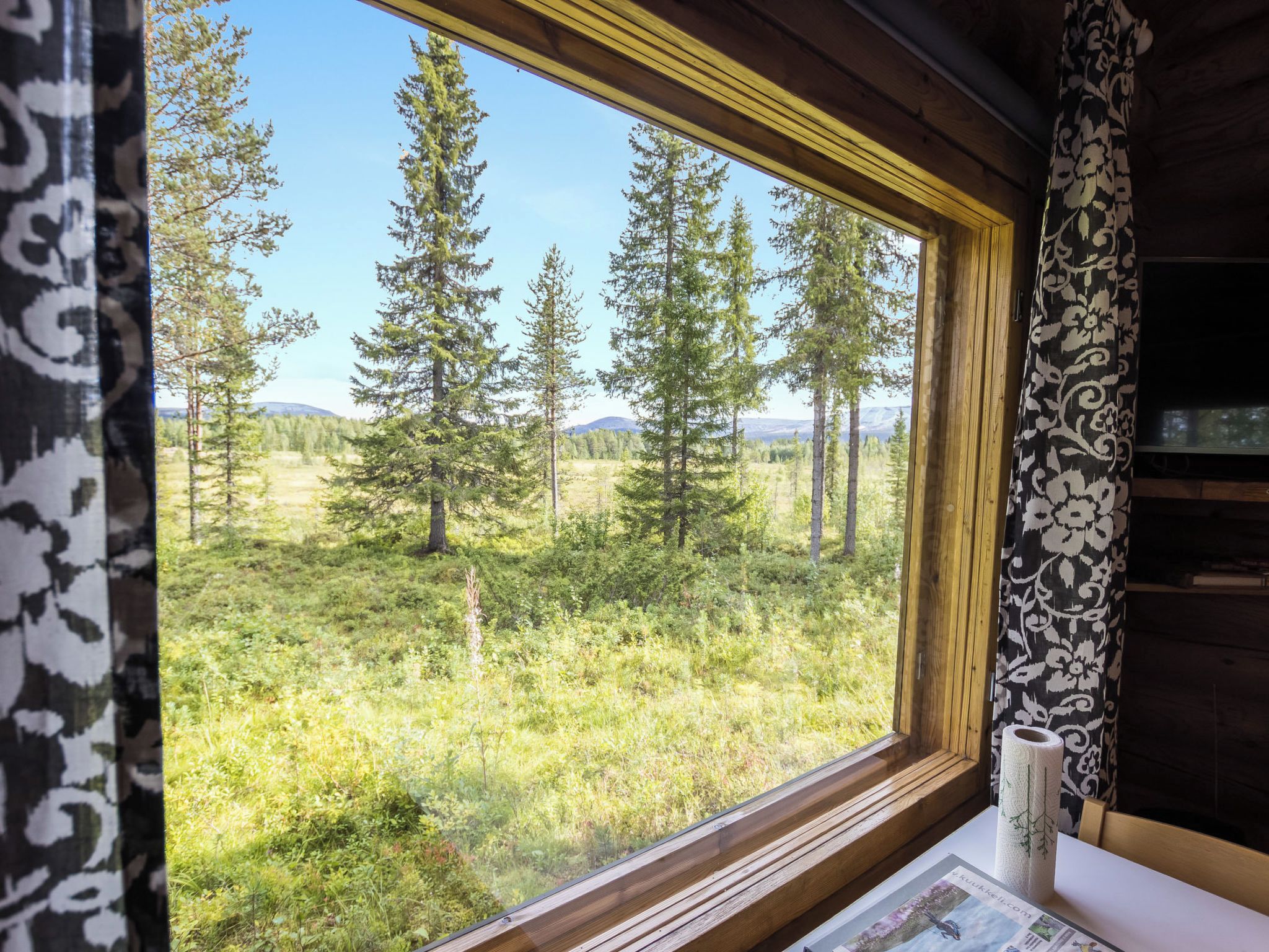 Huone, jossa on suuri ikkuna, josta avautuu näkymä metsään ja vuorille.