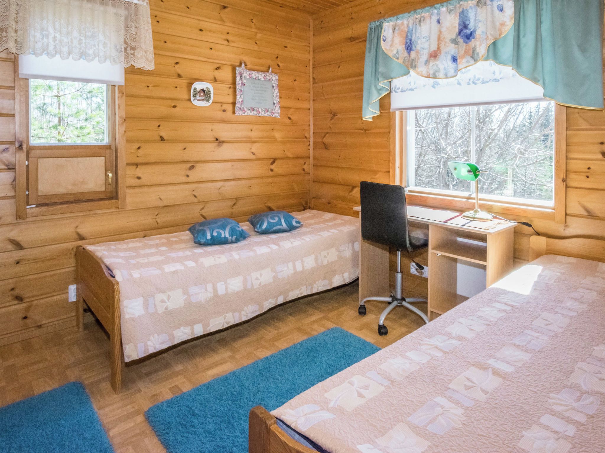 Une chambre dans un chalet en bois, avec deux lits, un bureau et une chaise.