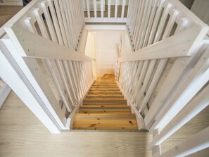 Un escalier en bois avec des rampes blanches menant à l’étage supérieur.