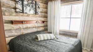 A bedroom with a bed, a wooden headboard, a window with curtains, and a wall-mounted shelf. - Maahisenrinne 1 as 4 by Interhome (Äkäslompolo)