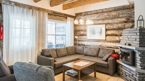 A cozy living room with a sectional sofa, a wooden coffee table, and a stone fireplace. - Maahisenrinne 1 as 4 by Interhome (Äkäslompolo)