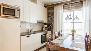 A modern kitchen with white cabinets, stainless steel appliances, and a wooden dining table with chairs. - Maahisenrinne 1 as 4 by Interhome (Äkäslompolo)