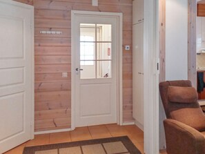 A wooden interior with a white door, a brown chair, and a tiled floor.
