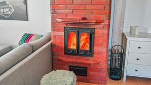 A living room with a red brick fireplace, a sofa, a fluffy rug, and a white cabinet. - Hovitahko a 1 by Interhome (Nilsiä)