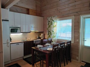 A compact kitchen with a microwave, sink, and dining area set for four.